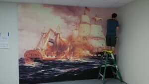 Josh installing a massive mural for a local museum